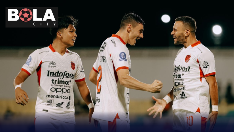 Pemain Bali United merayakan gol dalam pertandingan Liga Indonesia dengan seragam putih dan suasana stadion malam hari.